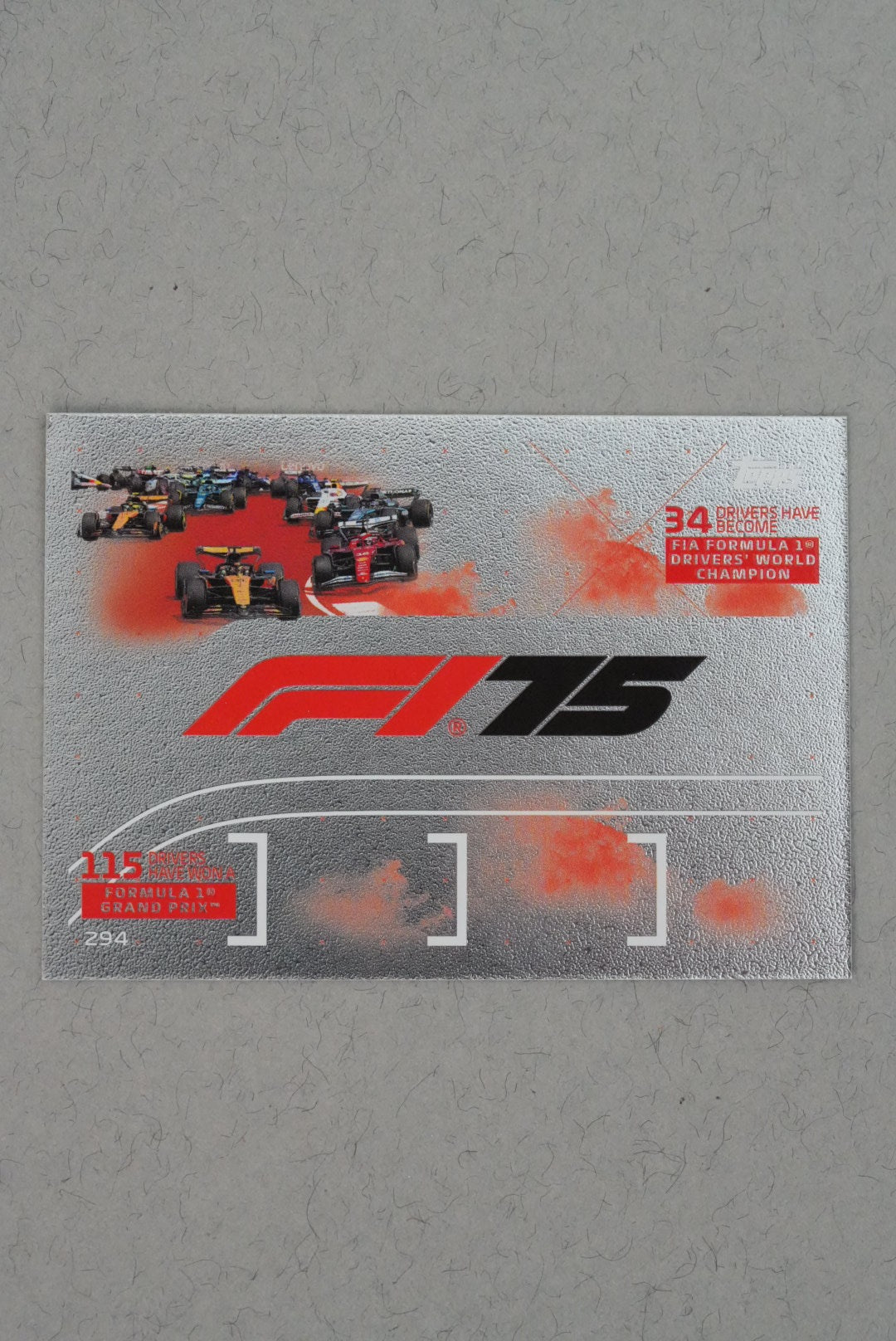 F1-themed promotional card with racing cars and 'F1' branding on a gray background