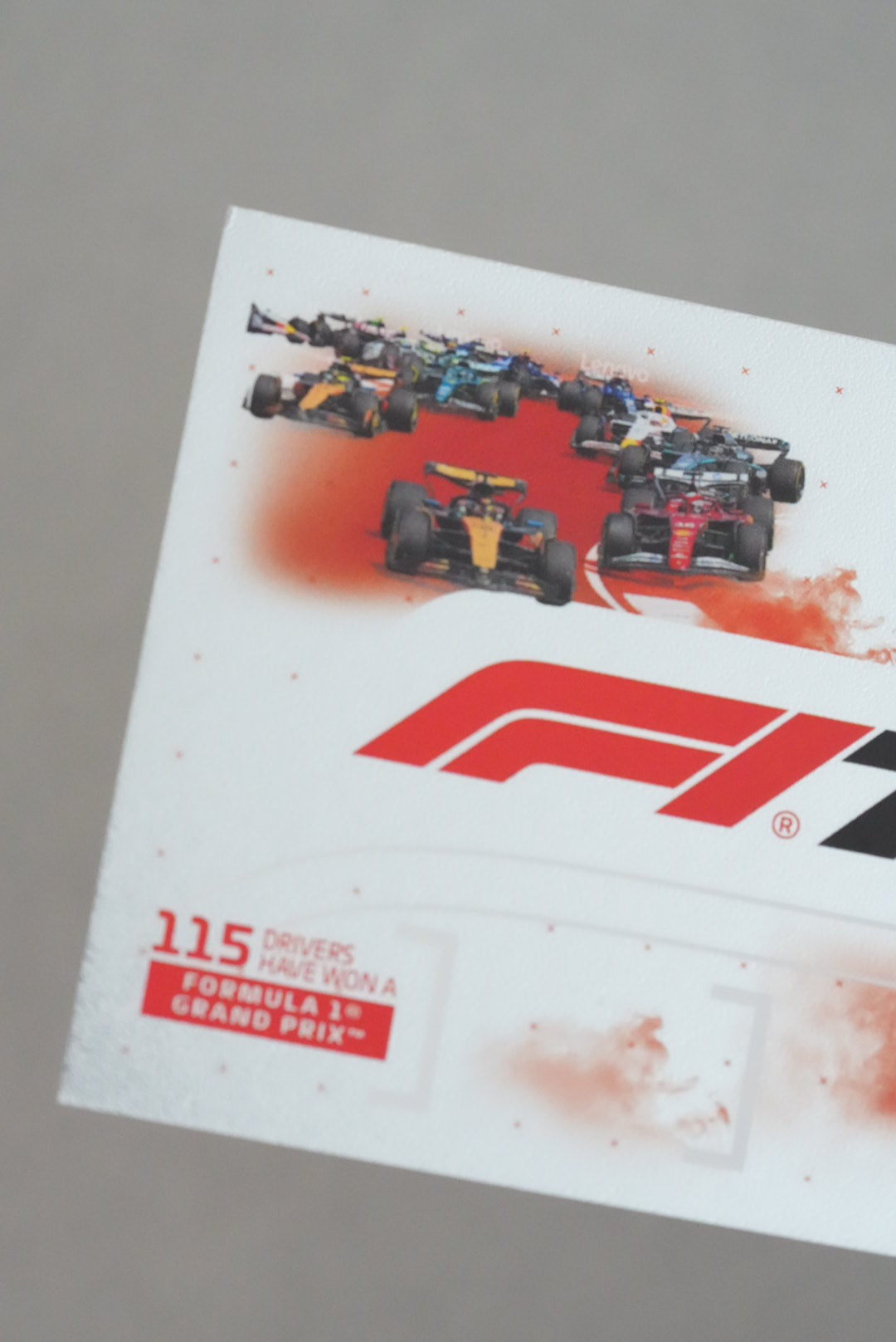 Formula 1-themed paper with race cars and branding on a gray background